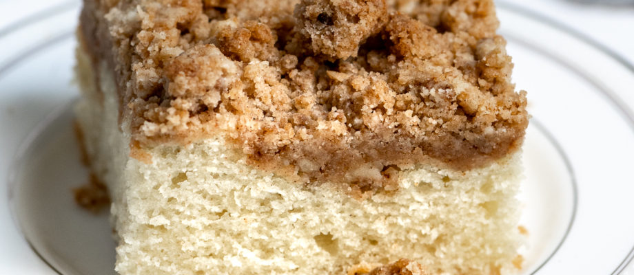 A slice of crumb coffee cake on a white plate.