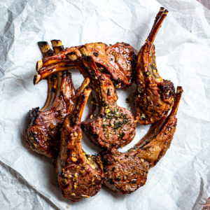 Grilled Greek style lamb chops on a few pieces of white parchment paper.